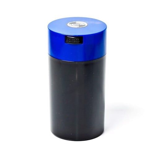 En transparent beholder med en glat, oval form præsenterer sig i en klar plastoverflade, der giver indblik til indholdet. Låget er fladt og udstyret med en trykknap i midten, der skaber et lufttæt forsegling. Farven er en lys blålig nuance, og beholderens kanter er bløde, hvilket giver et moderne udtryk.