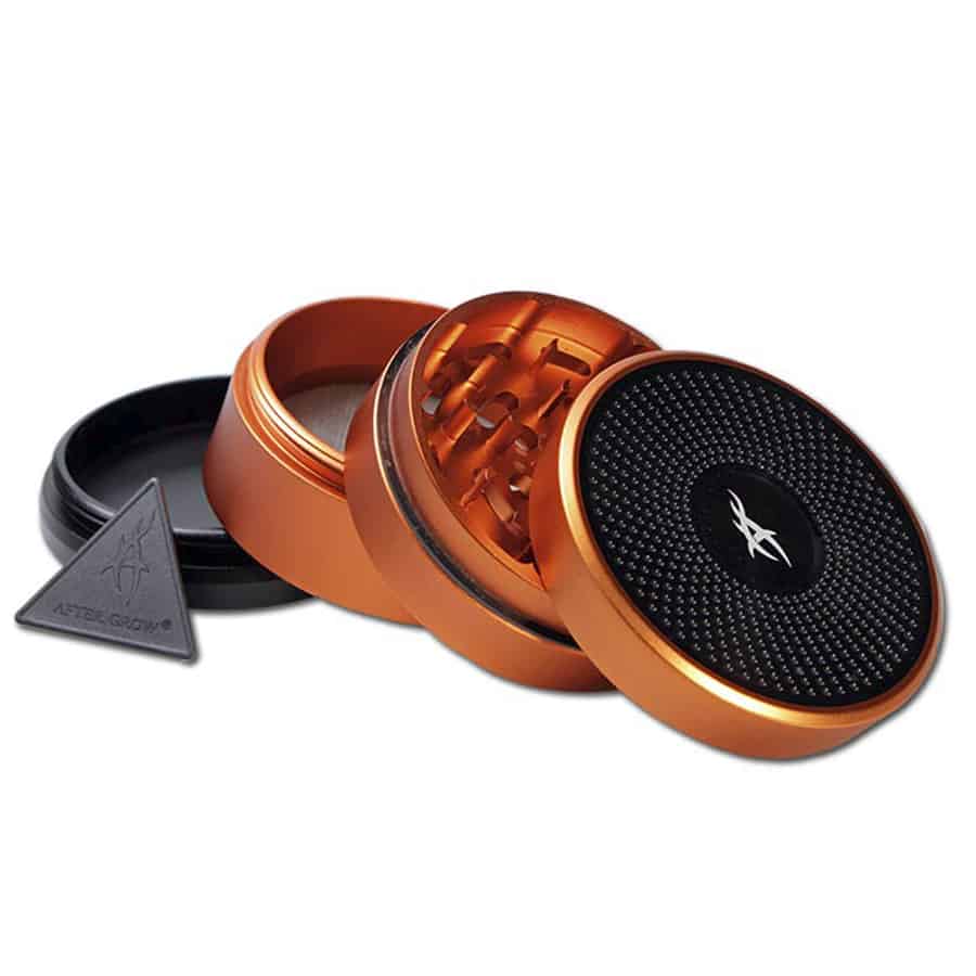 En orange krydderikværn med en glat, rund form og en sort, drejelig top. Kværnen har en struktur med fine ridser, der giver et godt greb. Den nederste del er transparent, hvilket afslører indholdet. Kværnen har en lille, cirkulær åbning til udslip af krydderi. Materialet synes at være plast, med en robust og holdbar finish.