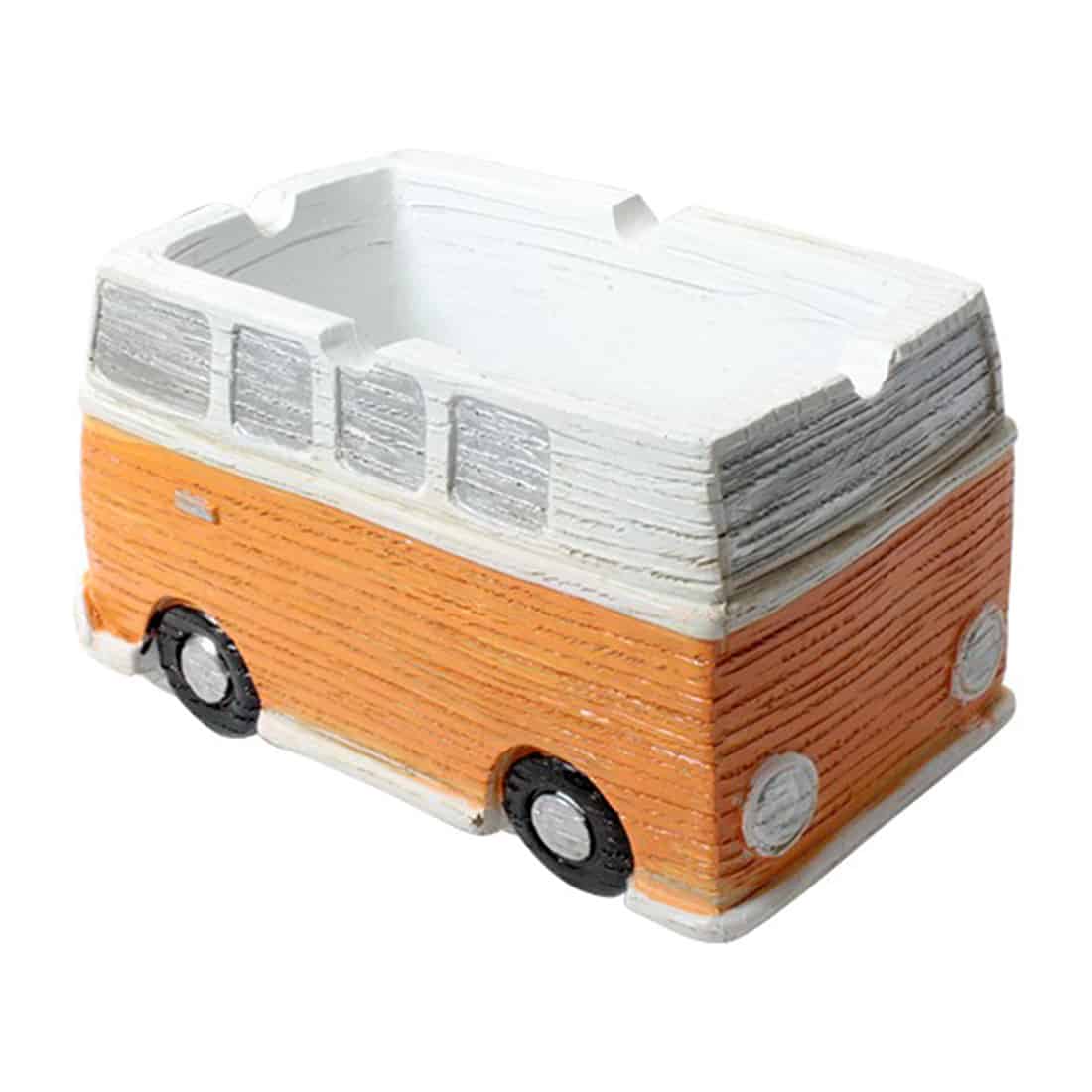 Et askebæger i form af en klassisk VW-bus præsenterer sig i en lys orange farve med glansfuld overflade. Formen er detaljeret med synlige vinduer, døre og hjul, der fremhæver busens ikoniske design. Kanten er let buet, og der er et lille hul til røg, der understøtter det funktionelle aspekt. Materialet er sandsynligvis keramik eller porcelæn.
