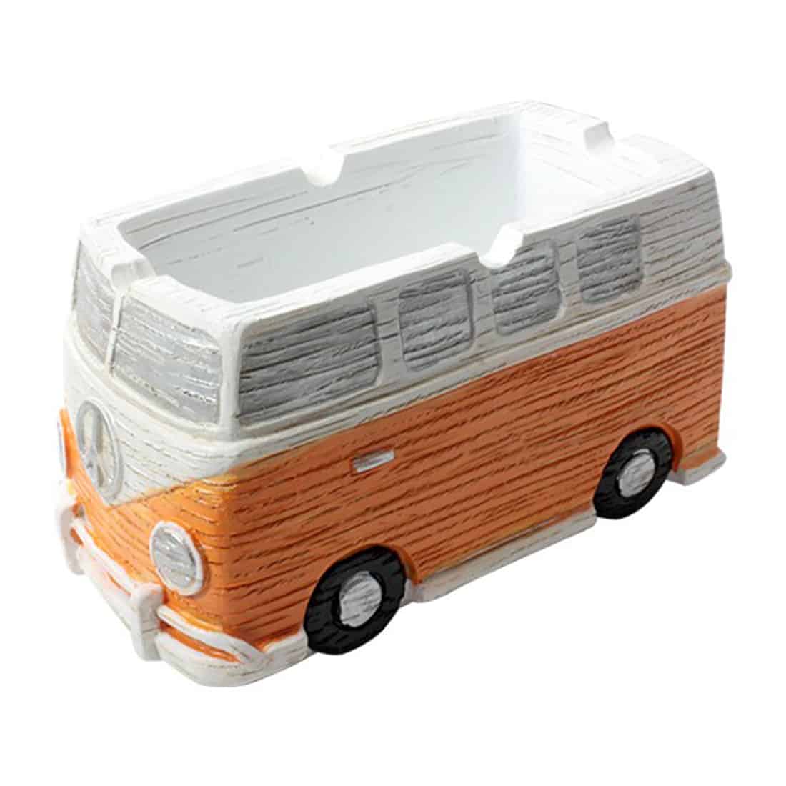 Et askebæger i form af en miniaturiseret Volkswagen-bus præsenteres i en livlig orange farve. Det har glatte, afrundede kanter og detaljer som vinduer og døre, der er skildret med sort og hvid maling. Bunden er flad og stabil, hvilket understøtter bægeret. Den blanke overflade reflekterer lys og fremhæver de farverige detaljer.