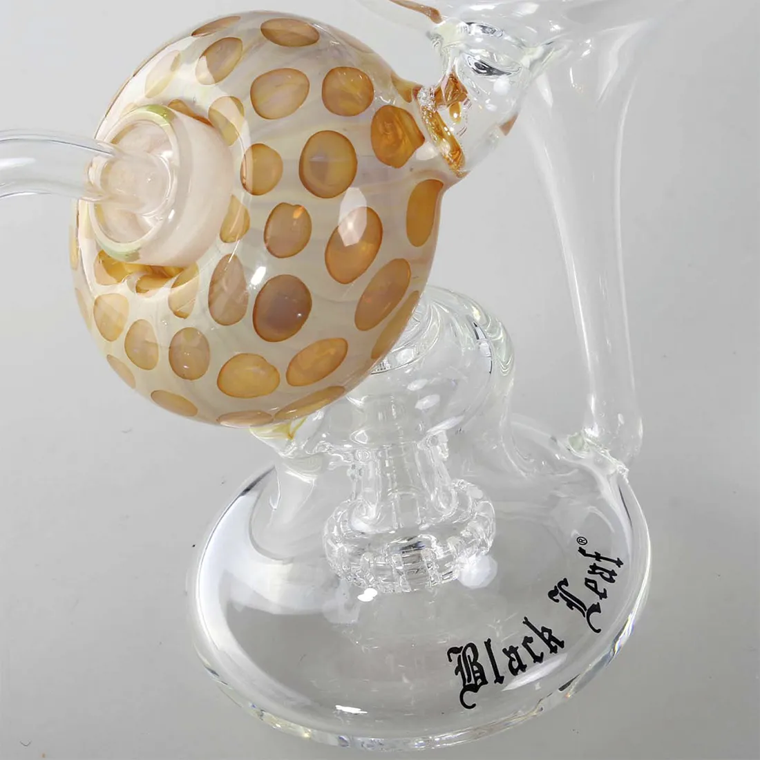 En skål med en dyb, sort farve og en glat, skinnende overflade pryder midten. Skålens form er rund med let opadbuede kanter, der skaber en elegant silhuet. Den indre del har et subtile mønster, der ligner blade, hvilket tilføjer tekstur. Materialet ser ud til at være genanvendt, hvilket giver den en unik karakter. Størrelsen måler 17 cm i diameter.