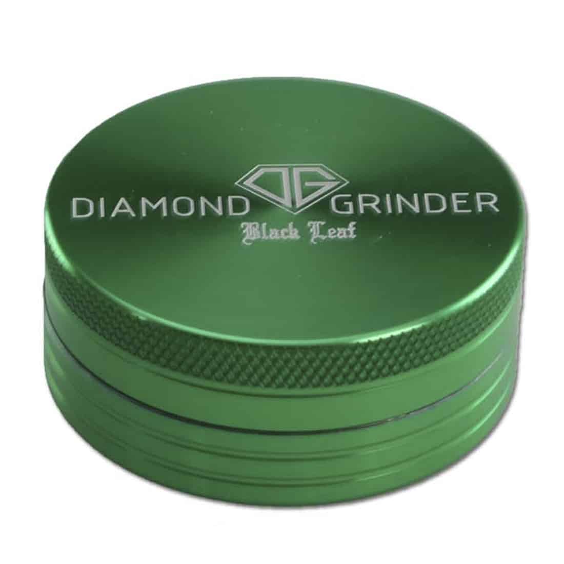 En sort, diamantformet plade med en mat overflade prydes af en elegant grøn bladform, der strækker sig diagonalt over pladen. Den grønne farve er intens og livlig, mens den sorte plade har en glat, ensartet tekstur. Kanten er skarpt defineret, og der er en tydelig kontrast mellem de to farver, der skaber et visuelt fokus.