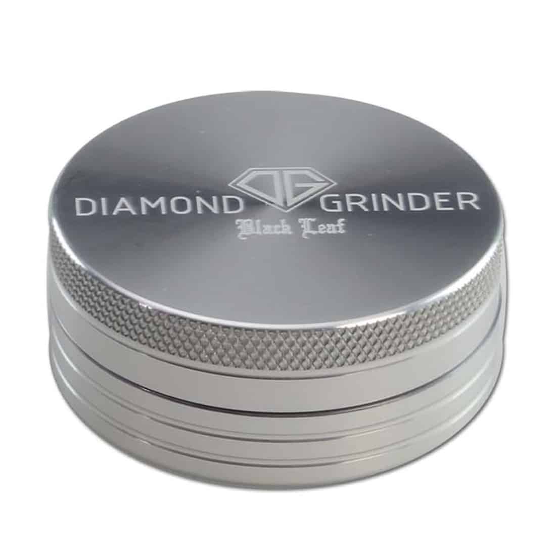 Et sølvfarvet smykke med en to-delt struktur præsenterer sig med en diamantformet vedhæng, der har en glat, reflekterende overflade. Vedhænget er prydet med en detaljeret, sort bladformet indgravering, der tilføjer dybde og kontrast. Kæden, som vedhænget hænger fra, er enkel med små led, hvilket skaber en harmonisk helhed.