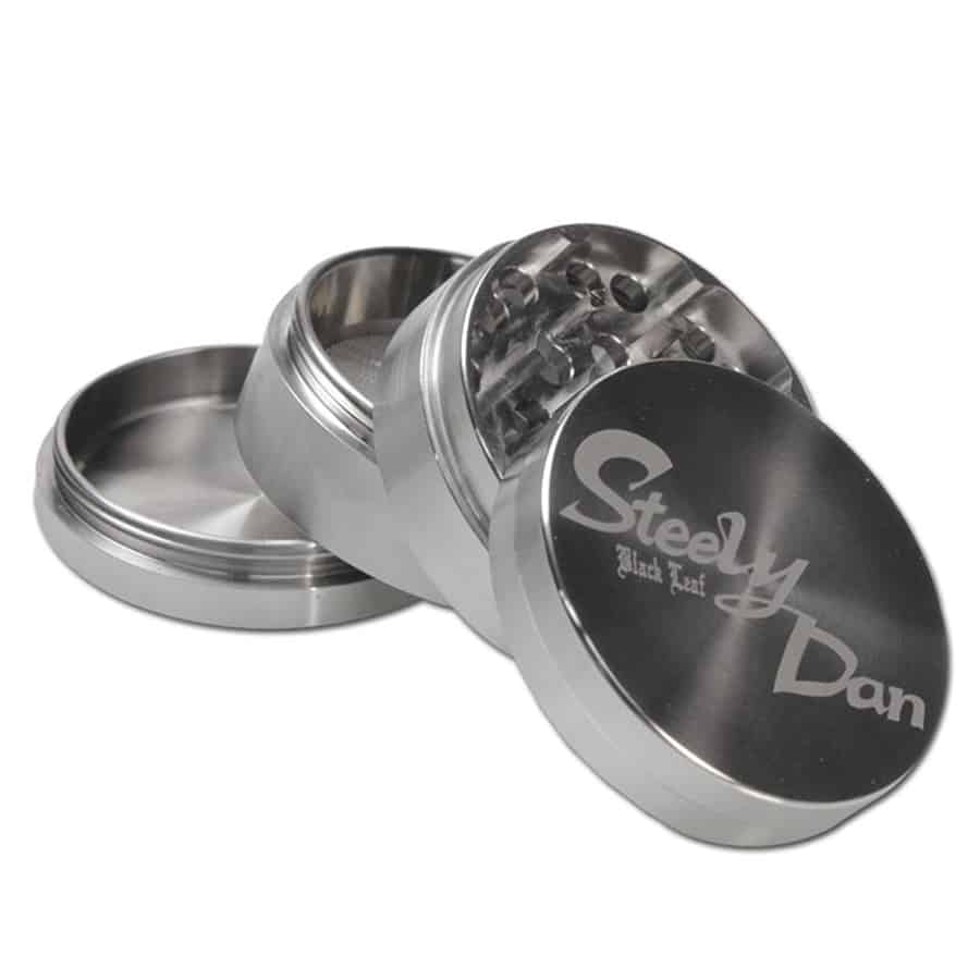 En sort plade med glat overflade prydes af et stiliseret mønster af blade, der strækker sig diagonalt henover. Bladene er detaljerede med fine årer, der giver dybde og tekstur. Farverne spænder fra dyb grøn til grålig sort, hvilket skaber en elegant kontrast. Kanten er let afrundet, hvilket tilføjer blødhed til det geometriske design.