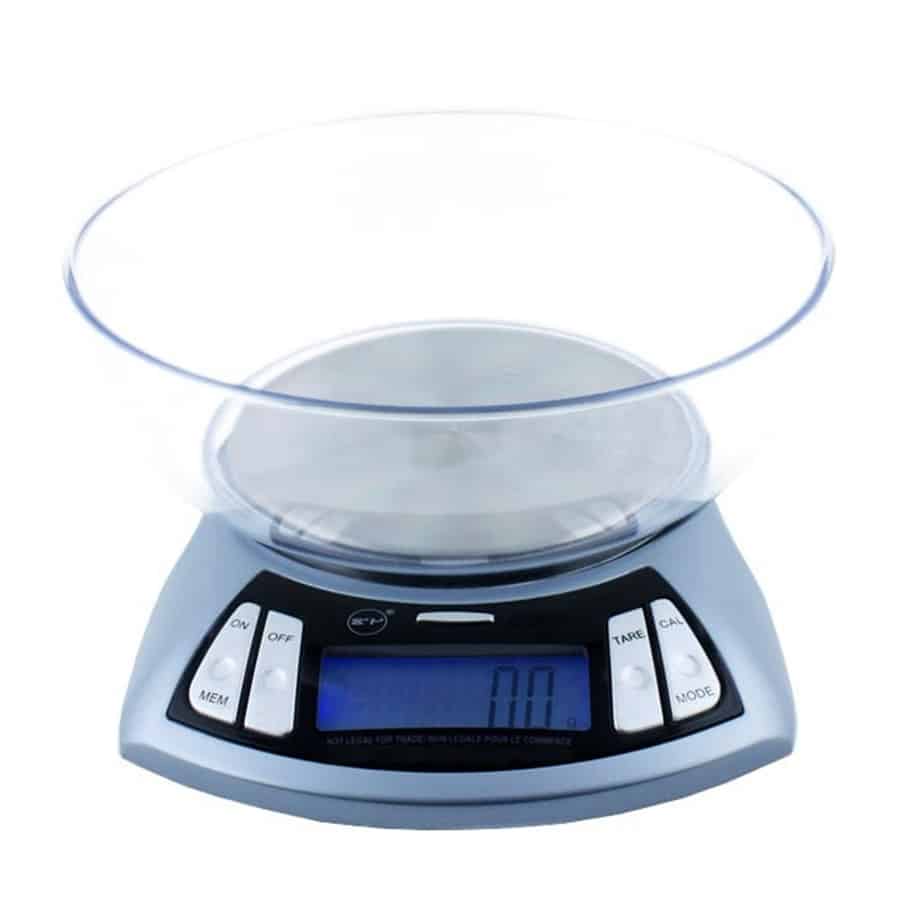 En kompakt, moderne enhed med en glat, sort overflade dominerer midten. På forsiden findes en digital skærm med tydelige tal og ikoner i hvid, der giver information om status. Knapperne er placeret på den nederste del, med en lysere farve, hvilket skaber kontrast. En let buet form tilføjer et strømlinet udseende, mens en ventilationsåbning ses på siden.