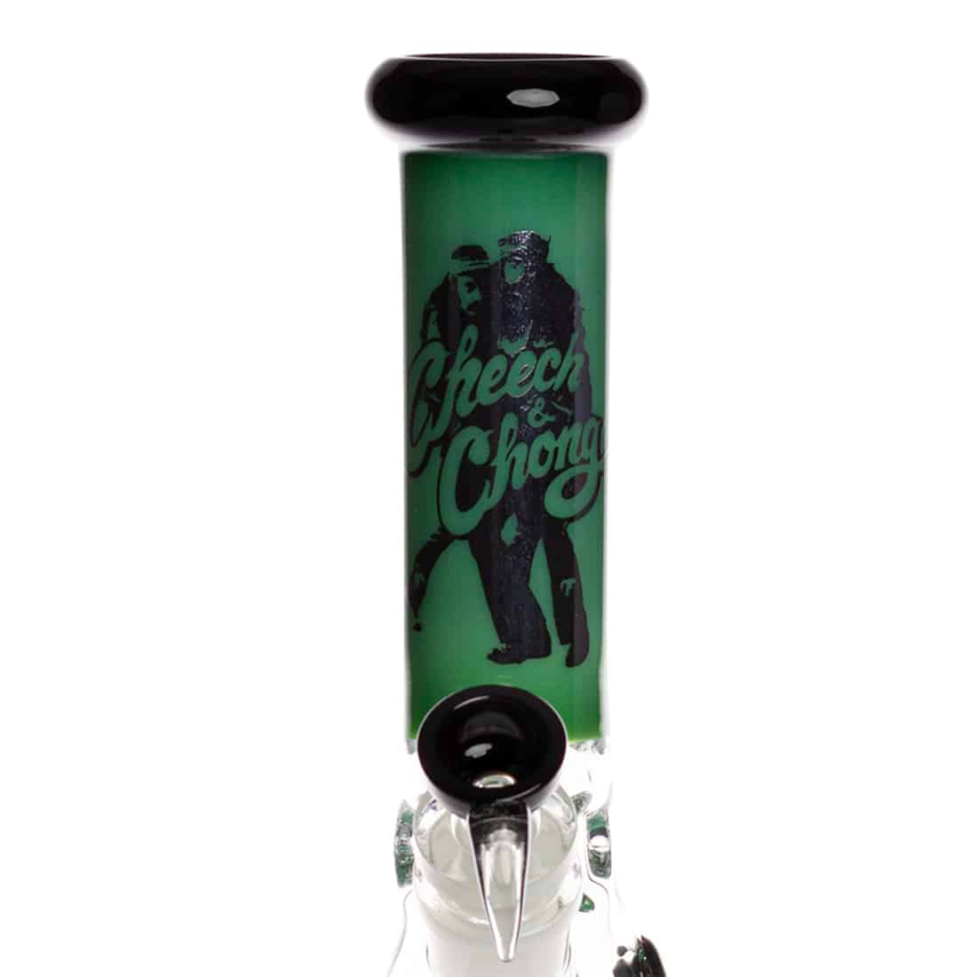 En beakerformet bong i klart glas med grønne detaljer. Den har en bred, stabil bund og en slank, opadgående hals. På siden er der en tydelig logo-etiket med grafiske elementer. Et integreret, nedadgående rør til vandfiltrering er synligt, sammen med en skål til tobaksprodukter. Overfladen er glat med en let reflekterende kvalitet.