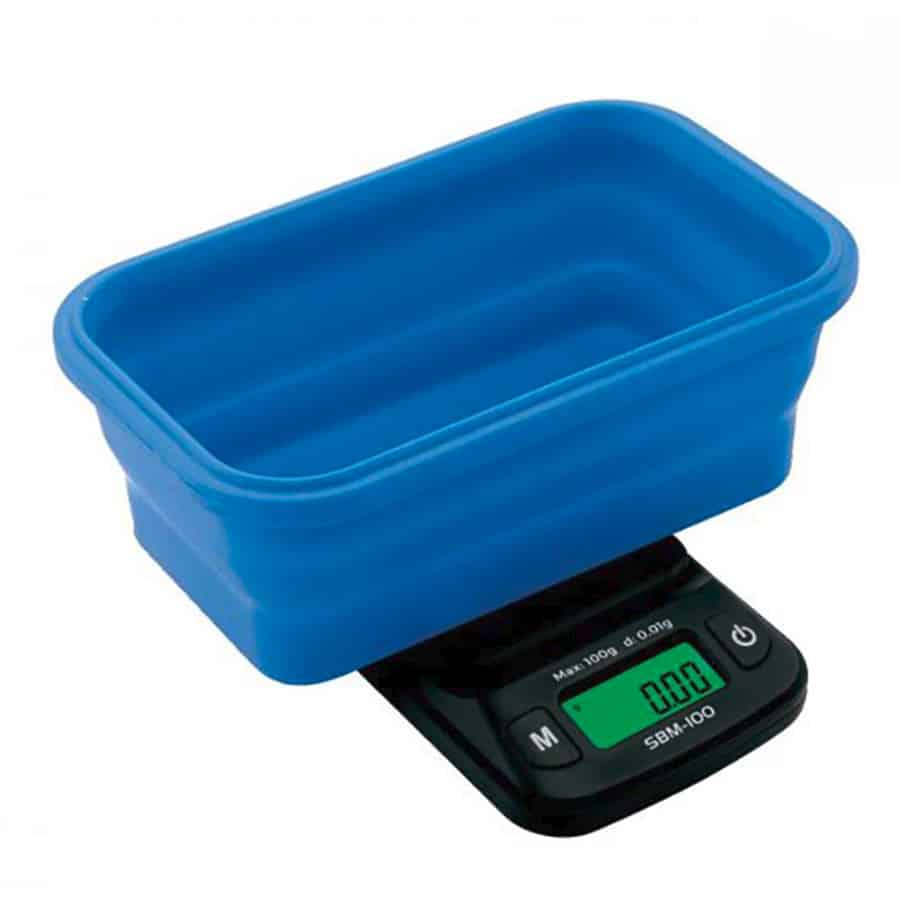 En digital vægt med en flad, rektangulær form og en sølvfarvet stålbase. Vægten har en gennemsigtig silikoneskål, der er placeret centralt, og skålen har en glat, rund kant. På vægtens overflade findes en tydelig digital skærm med sorte tal. Der er også synlige knapper i sort, som er placeret under skærmen.