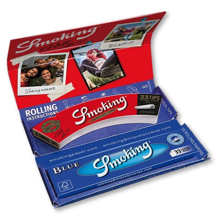 En luksuriøs rullesæt i blå farve præsenterer sig med en blød, tekstureret overflade. Indeni findes en række velordnet værktøjer, herunder en metalrullemaskine og en skuffe med små, fine papirark. Sættet har en elegant, minimalistisk stil, og de glatte, afrundede kanter giver et sofistikeret udtryk. Detaljer som syninger og knapper i metal tilføjer et eksklusivt præg.