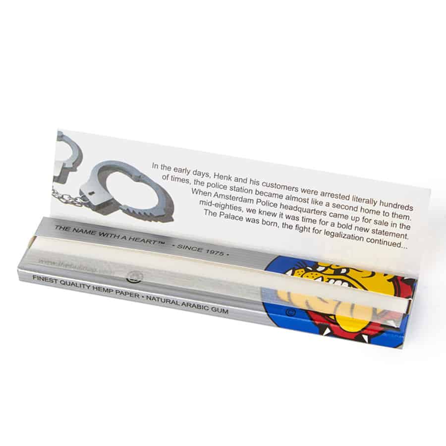 En sølvfarvet pakke med slank, rektangulær form præsenterer sig med en glat overflade. Forsiden har en mat finish, mens bagsiden er prydet med sort tekst og grafiske elementer. Bunden er åbnet, hvilket afslører en indhold af papir med en fin struktur. Kanten af pakken er let afrundet, hvilket giver et elegant udseende.