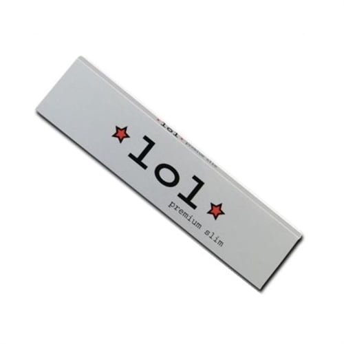 En lang, slank cigaretpakke præsenterer sig i en dyb blå farve med gyldne detaljer. På forsiden findes et stort, hvidt logo med en stiliseret skrift. Pakken har en glat, mat overflade, mens de gyldne accenter skaber en kontrast. Toppen er flad, og der er en let buet form i bunden, hvilket giver et elegant udtryk.