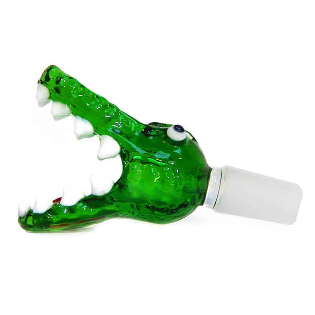 En skål i grønt kunstglas, formet som et krokodillehoved, præsenterer en glat, blank overflade med nuancer af mørke og lysegrønne toner. Skålen har detaljerede, strukturerede skalaer og en buet, organisk form, der skaber dybde og bevægelse. Kanten er let bølget, hvilket tilføjer en dynamisk karakter til det samlede design.