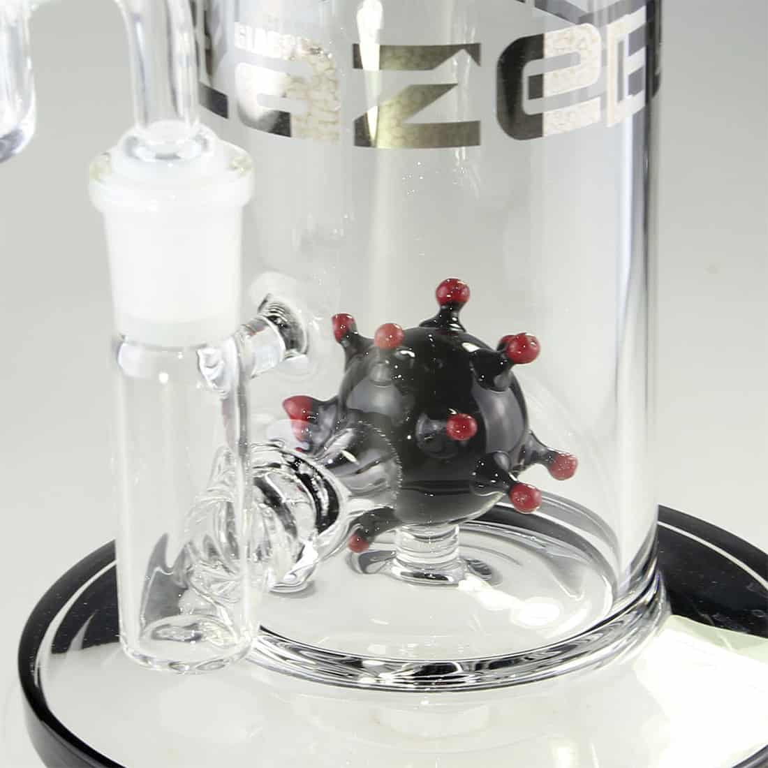 En sort glas-dab rig med en højde på 24 cm præsenterer en slank og elegant form. Den har en rund bund, som gradvist smalner op mod en buet hals. Riggen har en krum, transparent vandkammer, der skaber visuelle kontraster. På siden findes en lille, cirkulær åbning til dabber. Overfladen er glat med en blank finish, der reflekterer lys.