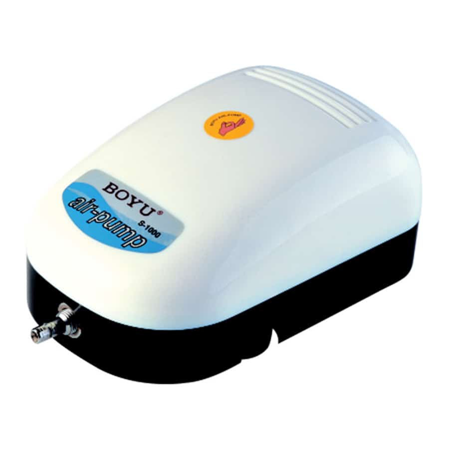 En luftpumpe præsenteres med en slank, sort plastikhus og en tydelig kontrolknap i midten. Pumpen har et rektangulært design med afrundede kanter og et gittermønster på fronten, der muliggør luftstrøm. En fleksibel slange er fastgjort til en udgangsventil, og der er tydelige markeringer for indstillingerne på siden.