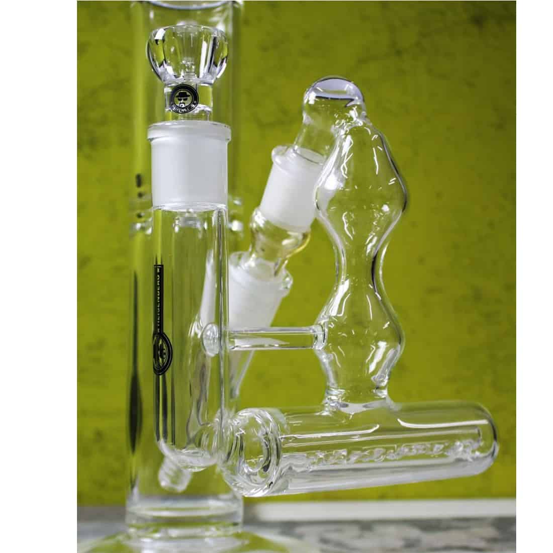 Heisenberg inline precooler præsenterer en slank, cylindrisk form i rustfrit stål med en poleret overflade. En række indgange og udgange er tydelige, hvor tubing kan tilsluttes. Overfladen har en glat tekstur, mens der er synlige svejsninger, der sikrer tæthed. En mærkat med tekniske specifikationer er placeret på siden, der tilføjer funktionel information.