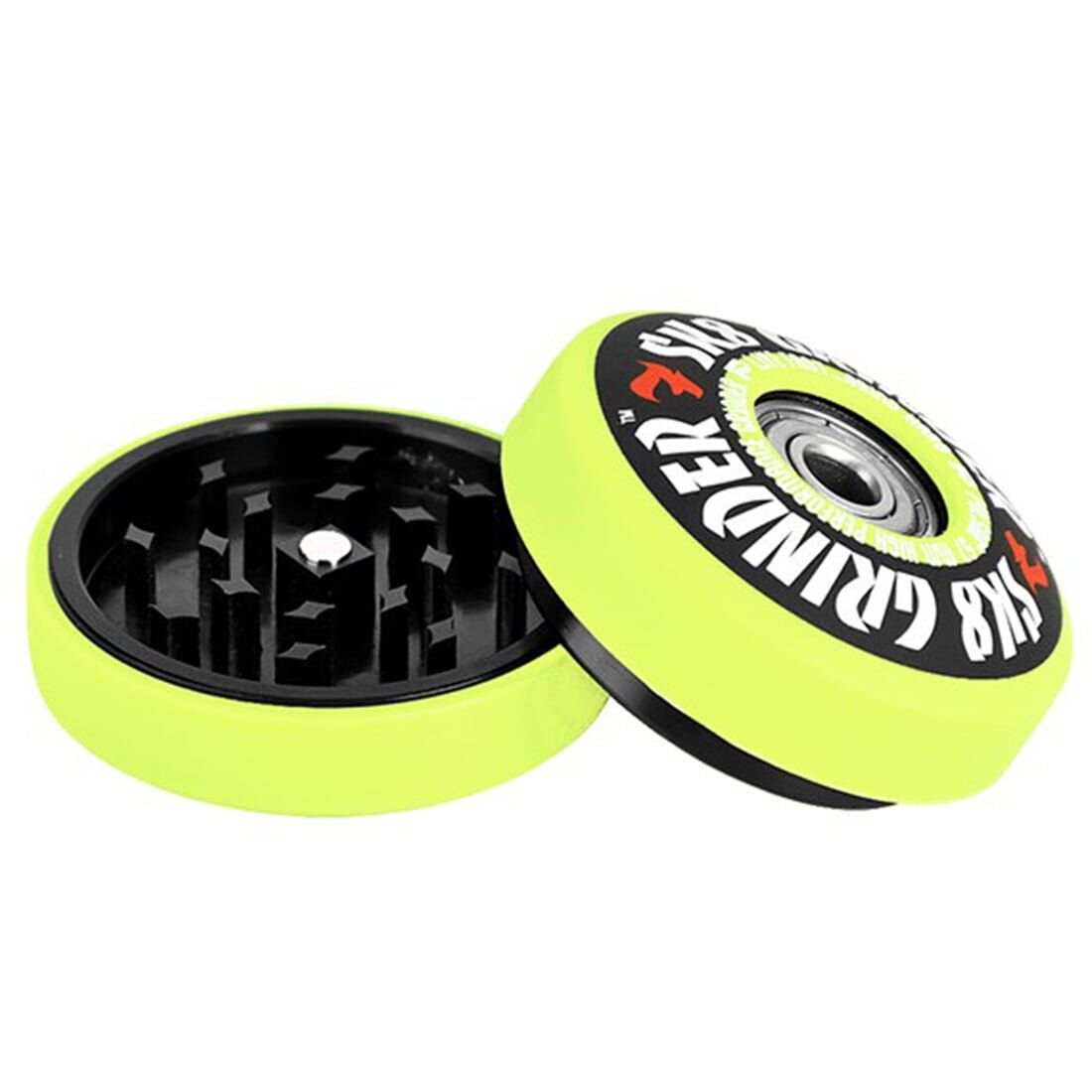 En grøn grinder med en skinnende overflade og en diameter på 57 mm. Den har en rund form med en let skridsikker tekstur på toppen. Der er synlige skarpe tænder indeni, som er designet til at male urter. Grinderen har en sølvfarvet, glat skruelåg, der giver en tætsluttende lukning. Den er prydet med et subtilt logo.