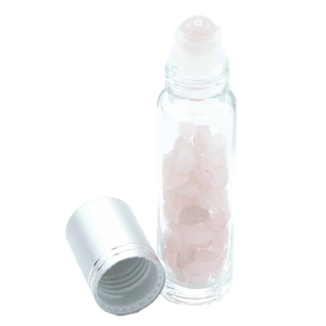 En rosenkvarts rollerflaske præsenterer sig med en blød, lyserød farve og en glat, gennemsigtig overflade. Flasken har en cylindrisk form med en rund, flad bund og en smal hals. Øverst sidder en metallic hætte, der holder en rulleapplikator, hvilket giver en elegant og funktionel finish. Materialet fremstår klart og refleksivt, hvilket fremhæver rosenkvartsens naturlige skønhed.
