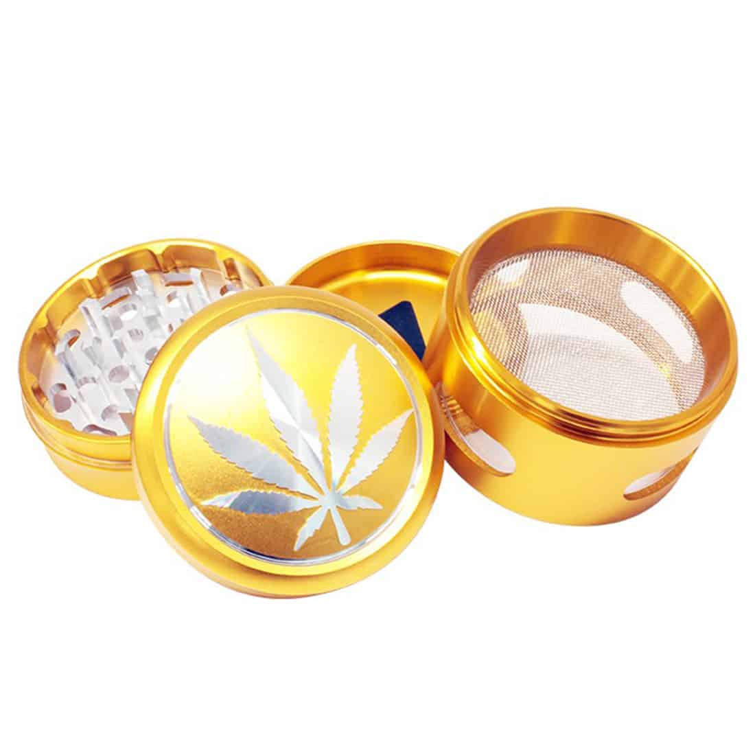 En guldfarvet kværn med en diameter på 63 mm præsenterer sig med en glat, metaloverflade, der glitrer let i lyset. Kværnen har en skarp tandstruktur indvendigt, der er designet til effektiv maling. Toppen er udstyret med en skruelukning og en lille, graveret logo, hvilket tilføjer et elegant præg. Kværnens form er cylindrisk med afrundede kanter.