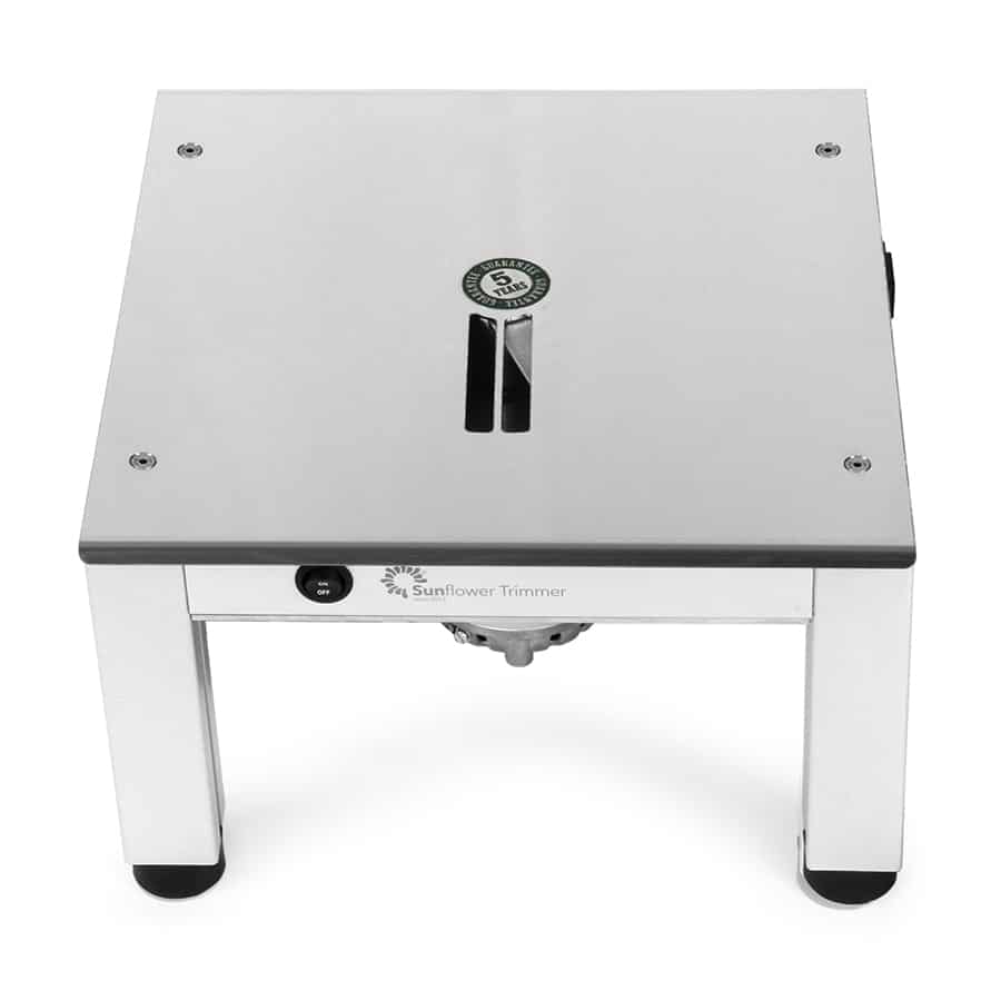 En lille, kompakt trimmer med en blød, sort gummibelægning, der giver et ergonomisk greb. Det har en rund, sølvfarvet knap øverst, omgivet af en mat sort overflade. Trimmerens krop har en slank, strømlinet form. Der er små luftkanaler langs siden, hvilket giver en let og moderne fremtoning. En fin, grøn indikatorlampe er synlig på forsiden.