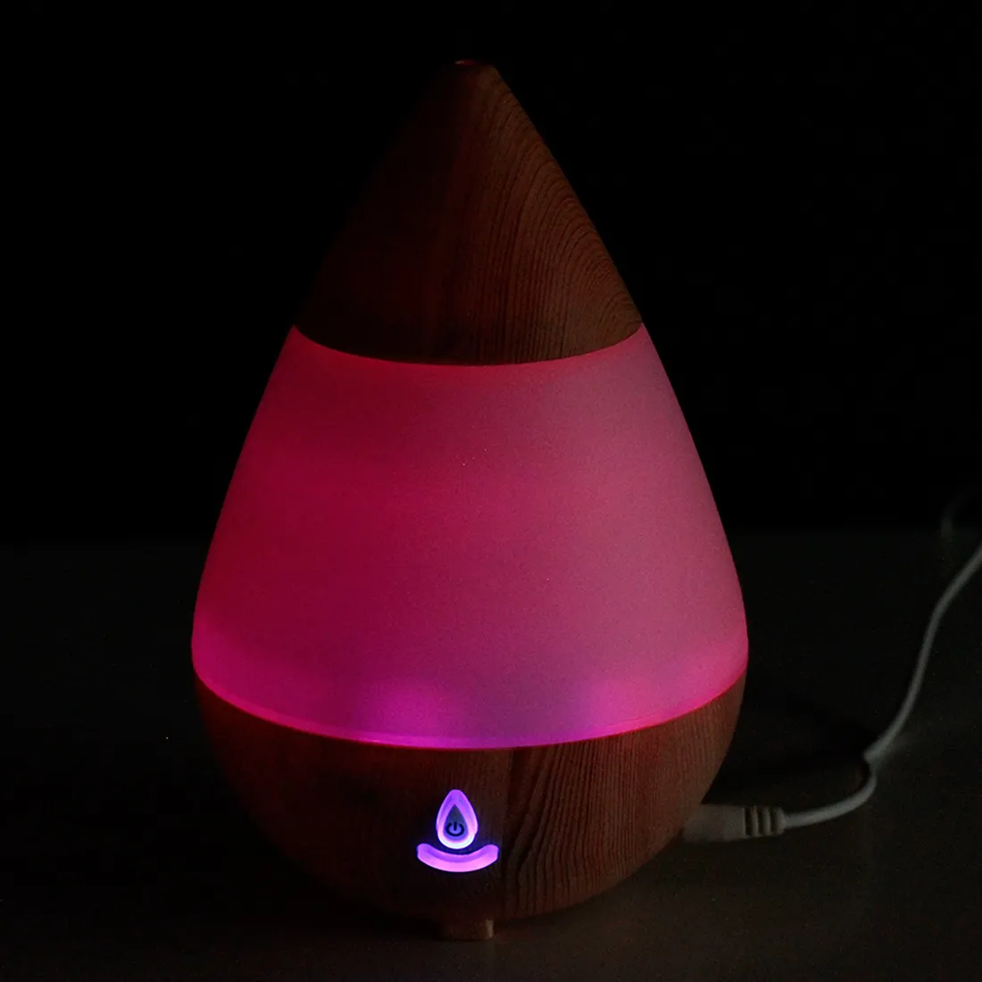 En dråbeformet aroma diffuser i lys træfinish med en glat overflade. Den har en rund bund og en tilspidset top, der giver et elegant udtryk. På forsiden er der en lille kontrolknap, der er indlejret i træet. Diffuseren har en diskret USB-port til tilslutning. Det samlede design udstråler naturlighed og enkelhed.