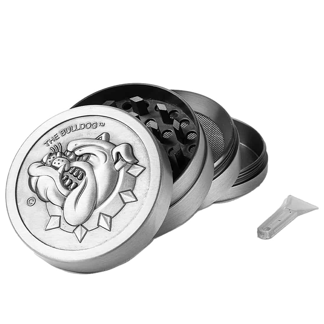 En rund metalgrinder med en diameter på 50 mm præsenterer sig i en mat, sølvfarvet overflade. Grinderens øverste del har en let skridsikker tekstur, mens den nederste del er glat. Indvendigt ses skarpe tænder, der er arrangeret i et mønster, der muliggør effektiv formaling. Kanten er let buet, hvilket giver et ergonomisk greb.