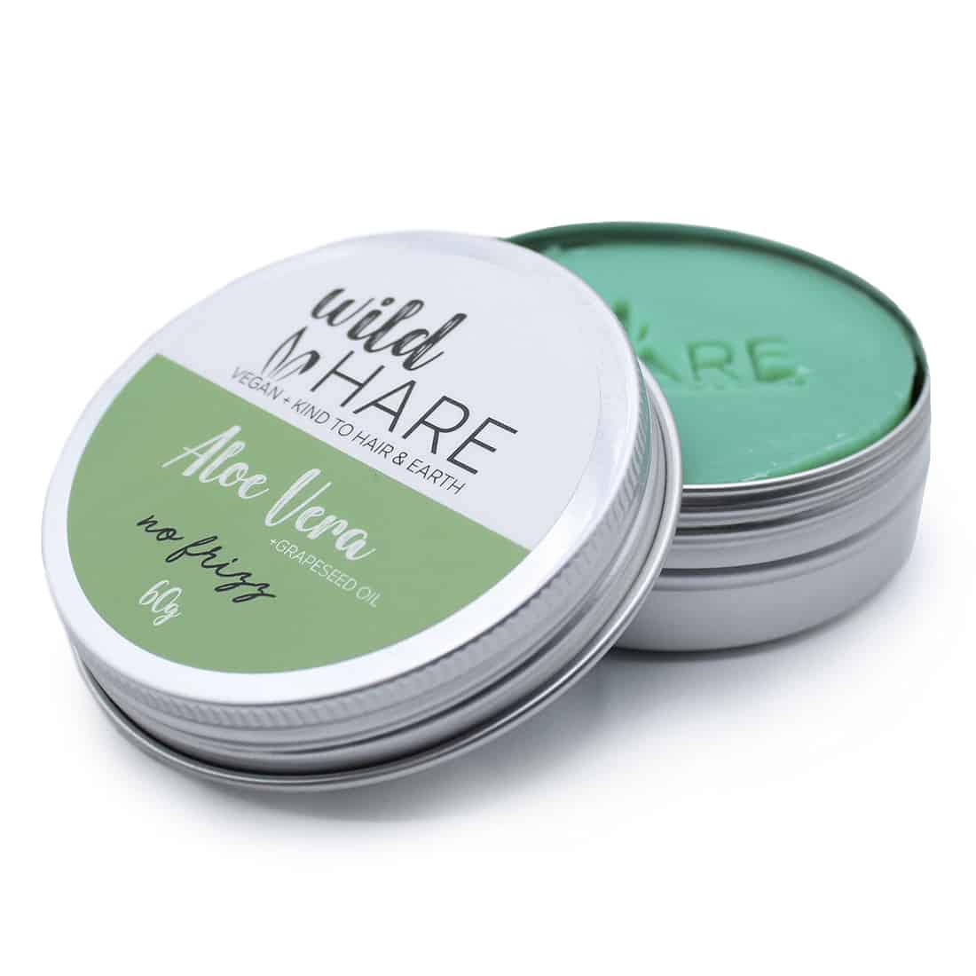 Rund, kompakt fast shampoo i en lys grøn farve med en glat overflade. Produktet har en let oval form og er præget med teksten "wild hare" i en enkel, sort skrifttype. En lille, hvid etikette med sort skrift angiver indholdet af aloe vera. Shampooen ligger på en lys, neutrale overflade.