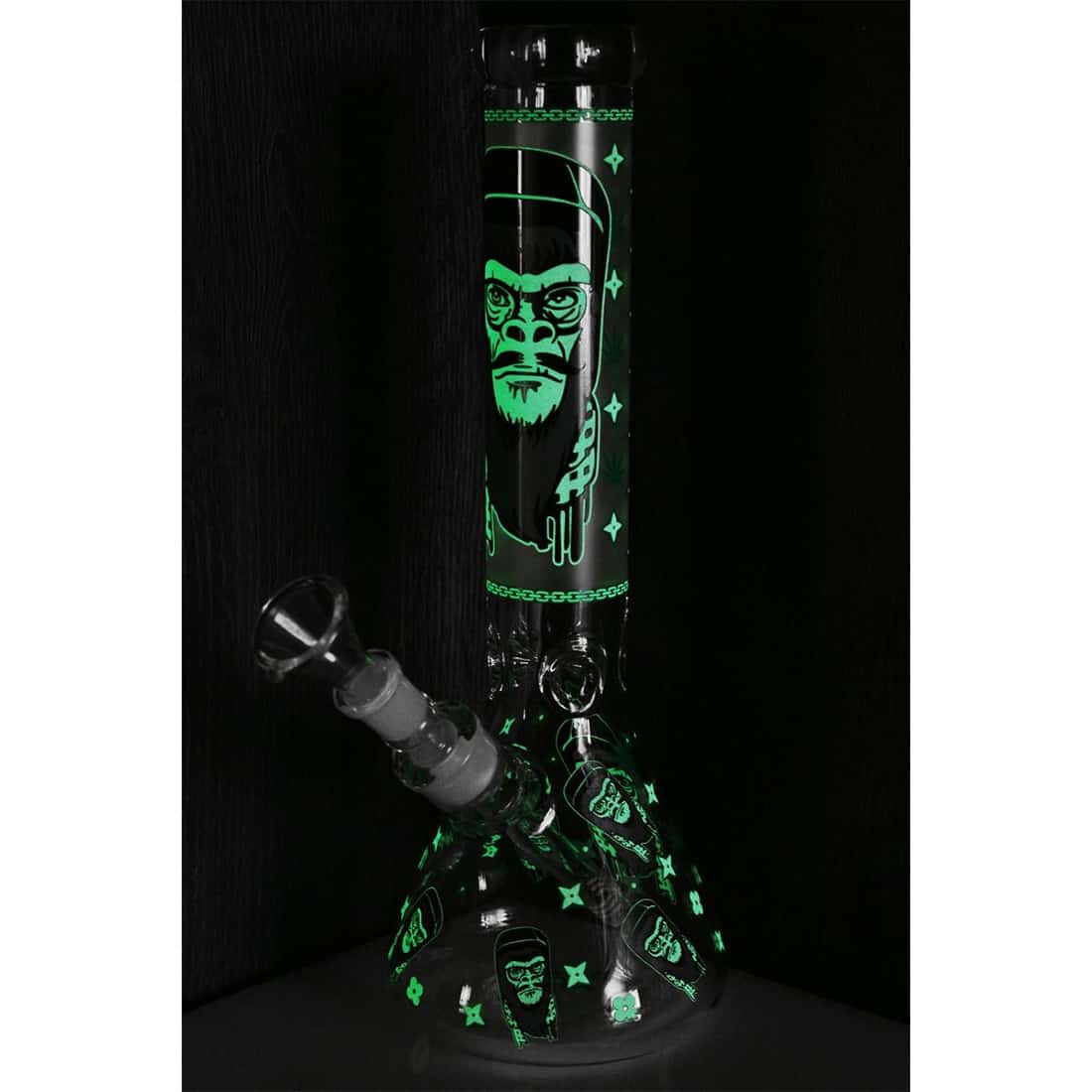 En grøn, glitrende apefigur med en glat overflade, der reflekterer lys. Figuren har store, udtryksfulde øjne og en bred mund, der giver et legende udtryk. Dens krop er rund og kompakt, mens lemmerne er proportionelt korte. I bunden er der en stabil base, der sikrer, at figuren står oprejst. Farven varierer fra lys til mørkegrøn, hvilket skaber dybde.