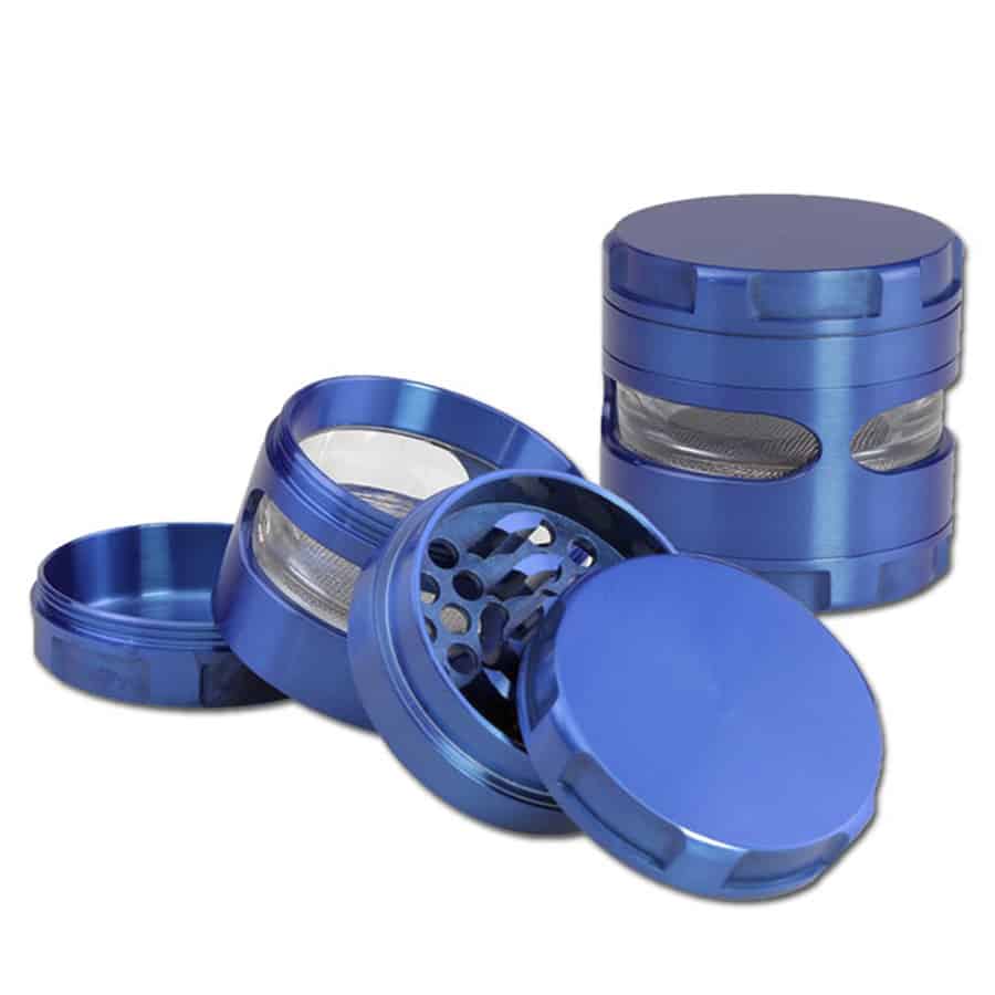 En rund metalgrinder med en diameter på 63 mm præsenterer sig i en mat sølvfarve. Overfladen har en let børstet tekstur, der skaber en subtil glans. Grinderens øverste del er udstyret med små, skarpe tænder til knusning. Der er en smal, indvendig kant, der adskiller de to sektioner. Ingen synlige mærker eller symboler pryder overfladen.