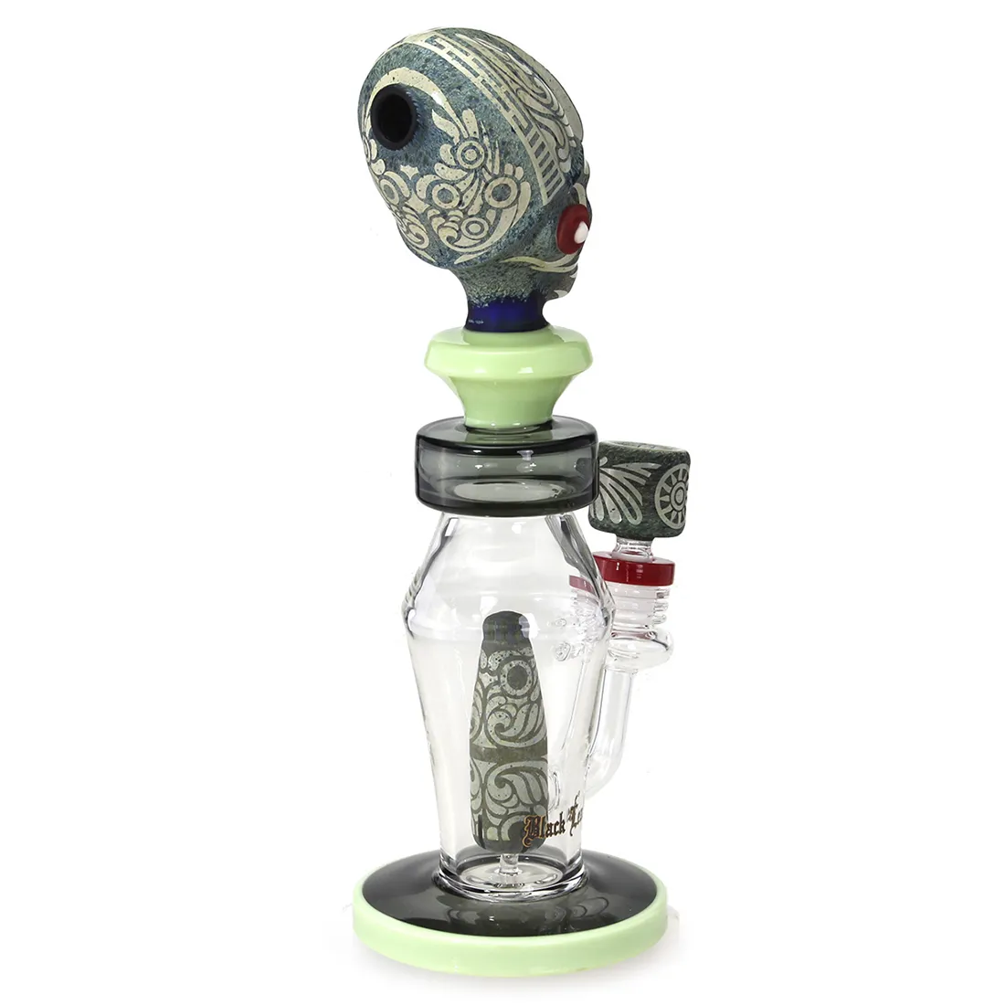 Diffusorbongen præsenterer en slank, sort glasstruktur med en høj, cylindrisk form. Den har afrundede kanter og en flad base, der sikrer stabilitet. En dekorativ, bladformet detalje pryder siden. Bongen indeholder et indbygget perkolator-system, der skaber komplekse vandmønstre, og den har en sideåbning til mundstykket. Overfladen har en glat, reflekterende finish.