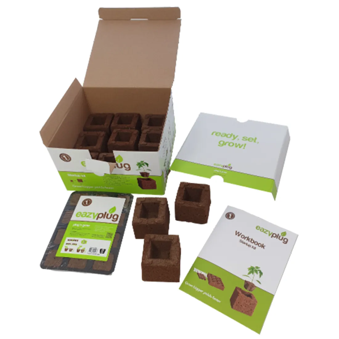 Et hvidt plastikbeholder med en gennemsigtig top, der indeholder flere små brune jordklumper. Beholderen er firkantet med afrundede hjørner og har en skridsikker bund. På toppen er der en etikette med farverig tekst og symboler, der angiver brugen. Indholdet ser friskt og fugtigt ud, og der er en lille åbning til vanding.