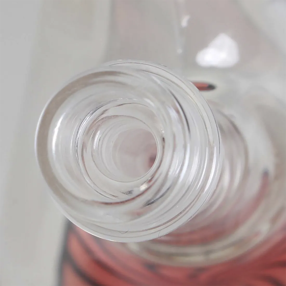 En sort glasbong med en slank hals præsenterer sig med en elegant form. Den har en rund bund, der giver stabilitet, og en glat overflade, der reflekterer lyset. Bongen har en indbygget perkolator og en skarp kant, der skaber et stilrent udtryk. Det sorte glas fremhæver det minimalistiske design og sikrer et moderne udseende.