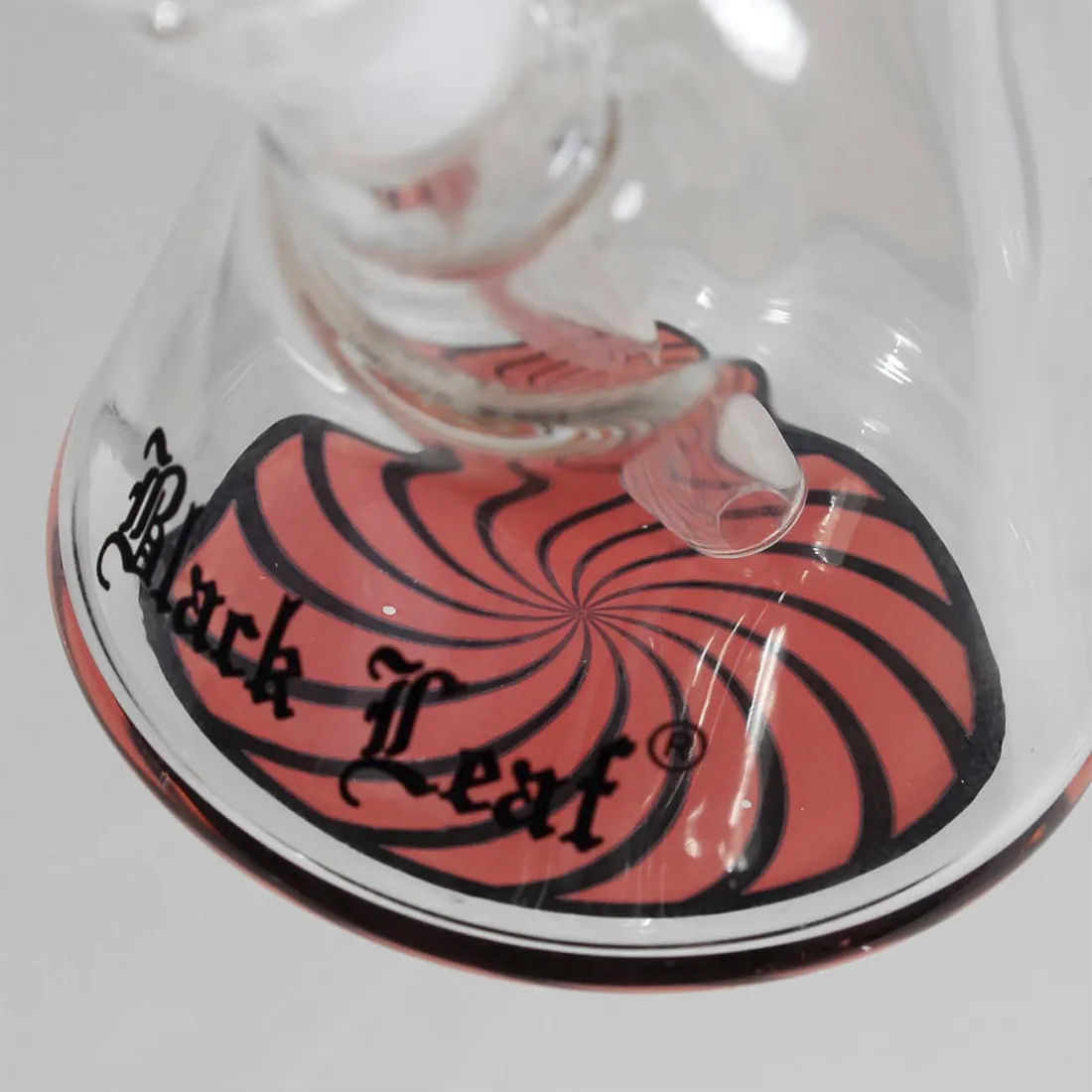 En elegant, sort bong med en slank hals og et stilrent design. Den har en rund base, der giver stabilitet, og en glat overflade, der reflekterer lys. Det sorte glas har en dyb, ensartet tone. Bongens hals er lang og smal, hvilket skaber en harmonisk silhuet, mens det nedre segment har en subtil, let buet form.