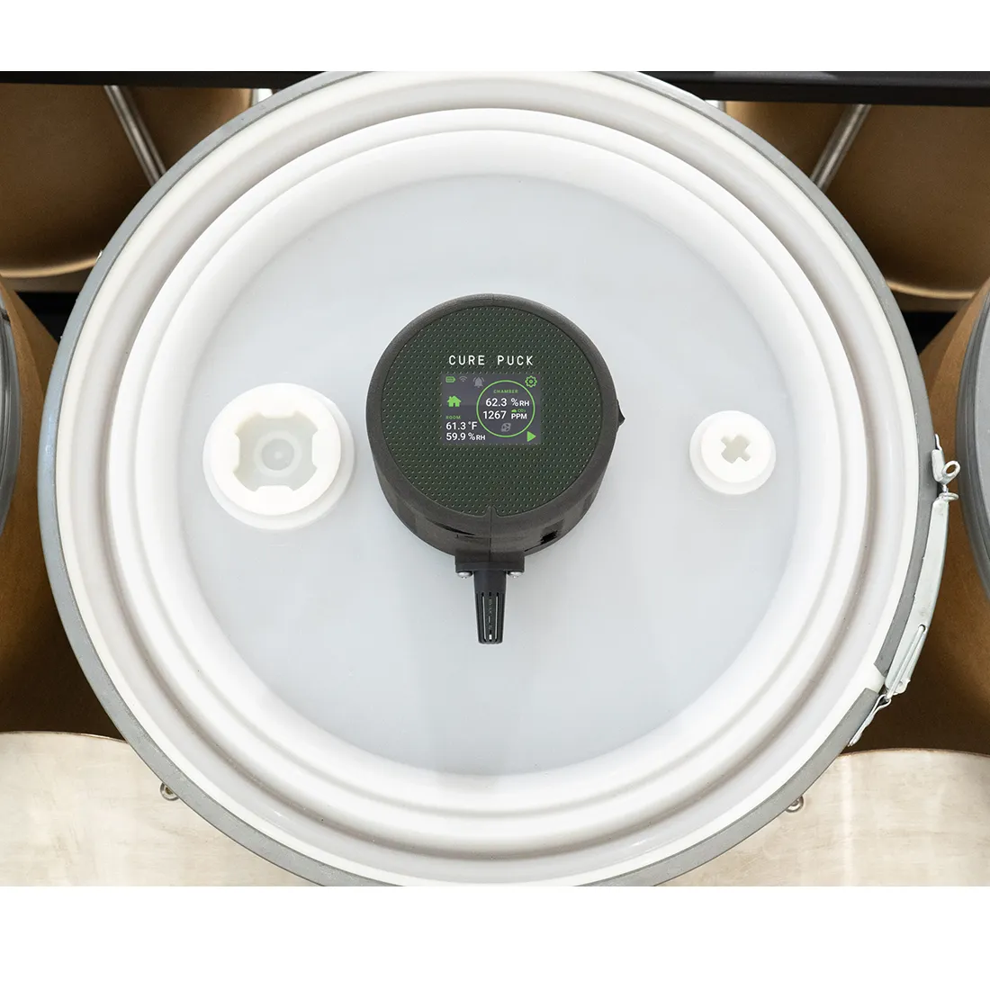 Cirkulær puck i klar plast med en diameter på cirka 10 cm. Overfladen er glat og gennemsigtig, hvilket giver mulighed for at se indholdet. Farven er en lys grå, og der er en let blødhed i materialet. Pucken har en flad, ensartet kant og en subtil tekstur, der kan give et godt greb.