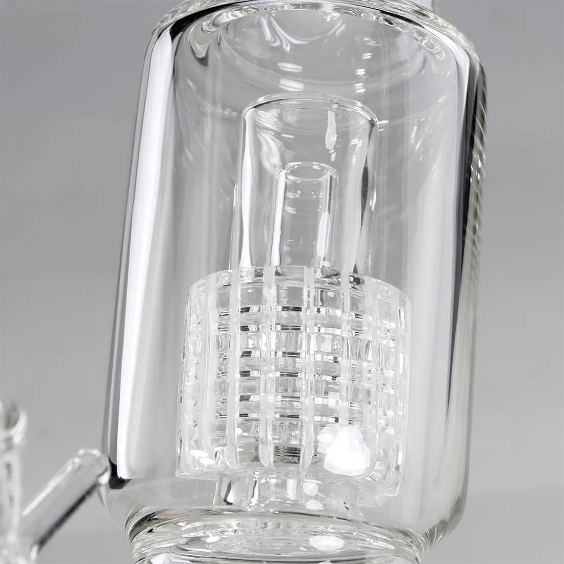 Glasrøret har en transparent, glat overflade med en let buet form. Det er dekoreret med farverige, mønstrede detaljer i nuancer af blå, rød og orange, der skaber en dynamisk visuel effekt. Perkolatoren i bunden har små runde åbninger, der giver en struktureret tekstur. Kanten er forsynet med en bred åbning, der muliggør tilføjelse af is eller vand.