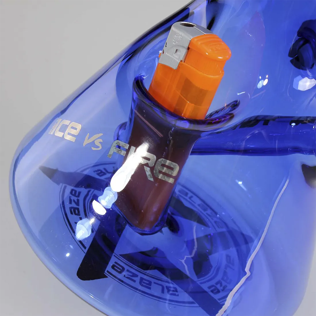 Glasvase med tofarvet design, hvor den øverste del er klar og den nederste del er dybblå. Vasen har en slank, cylindrisk form med let buede kanter. Indeni er der en perkolator med flere små rør, der strækker sig opad. Overfladen er glat, med reflekterende egenskaber, der fremhæver farvekontrasten mellem de forskellige sektioner.