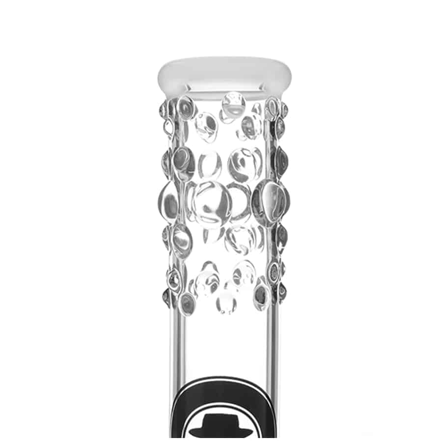 En stor, klar glaskolbe med en bred bund og smal hals pryder midten, hvor væsken bobler opad. Kolben har en rund form, og væsken skifter farve fra dyb blå til klar. Overfladen er glat og skinnende, mens kolbens kant er tynd og præcist afsluttet. Den står på en hvid overflade, som skaber kontrast til den klare glasstruktur.