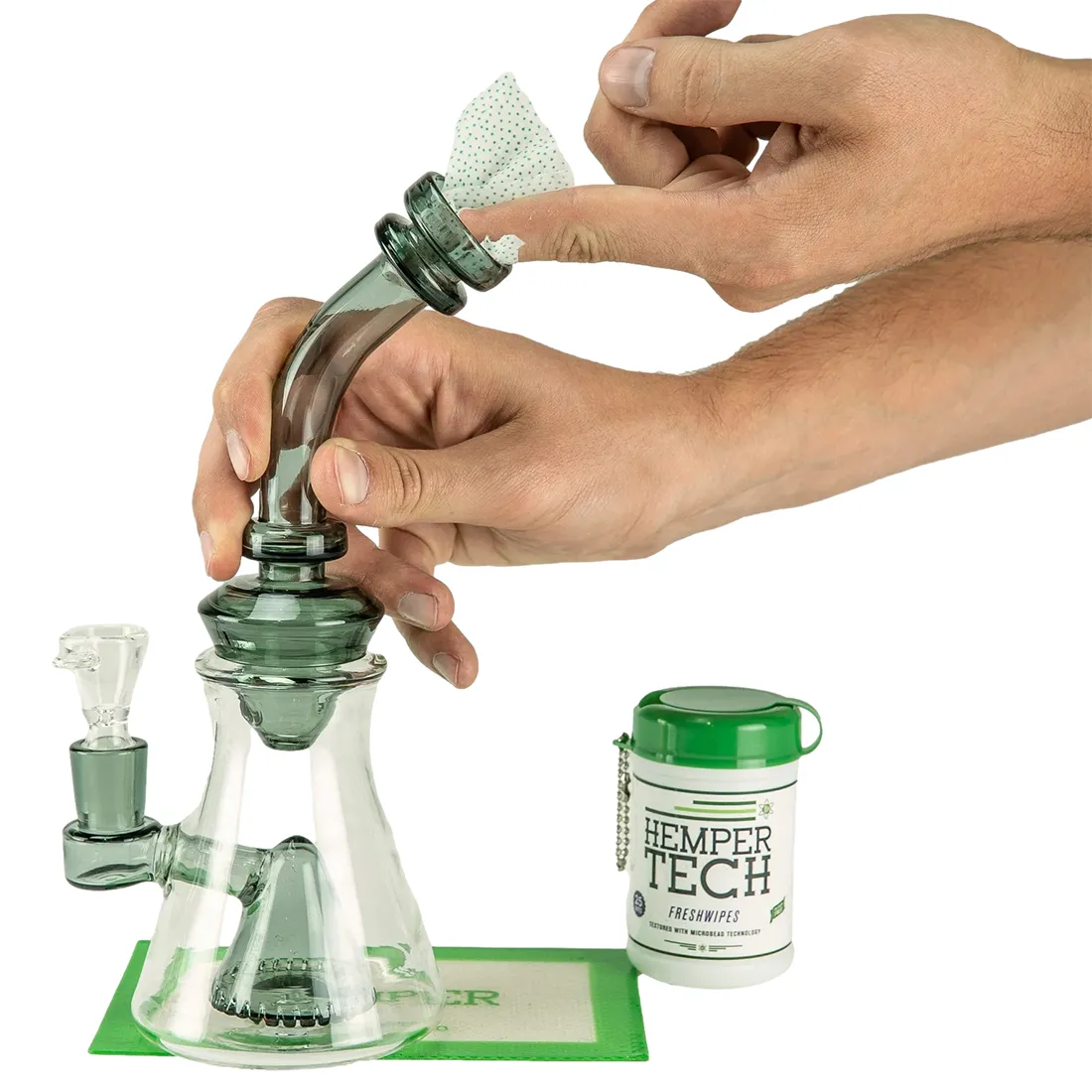 Friskduftende vådservietter præsenteres i en hvid emballage med grønne og blå detaljer. Forsiden bærer tydelig tekst med produktnavnet i en moderne skrifttype. Emballagen har en praktisk åbningsklap øverst, der sikrer nem adgang til servietterne. Baggrunden er enkel og lys, hvilket fremhæver farverne og designet på pakken.