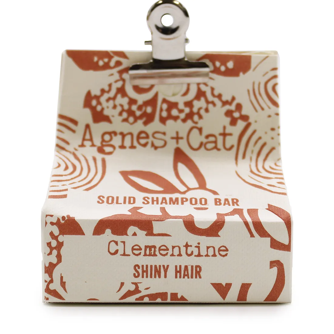 En solid shampoo bar i en rund form med en glat, ensartet overflade. Farven er lys orange, der ligner en clementin. Overfladen viser en let tekstur med små, subtile ujævnheder. Ingen synlige emballager eller indpakning. Der er ingen synlige symboler eller tekst, hvilket giver et minimalistisk og naturligt udtryk.