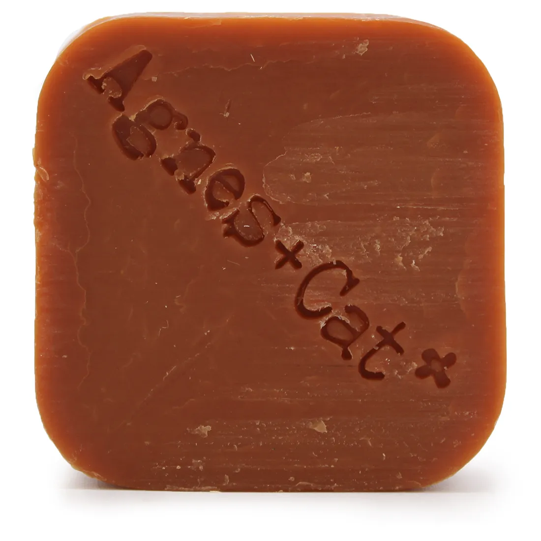 Den solide shampoo-bar har en rund, flad form med en glat overflade. Farven er en varm, lys orange, der udstråler en blød og cremet tekstur. Der er tydelige, subtile mønstre på overfladen, som tilføjer dimension. Baren prydes af en enkelt, stiliseret prikket detalje, der skaber visuel interesse uden at være overfyldt.