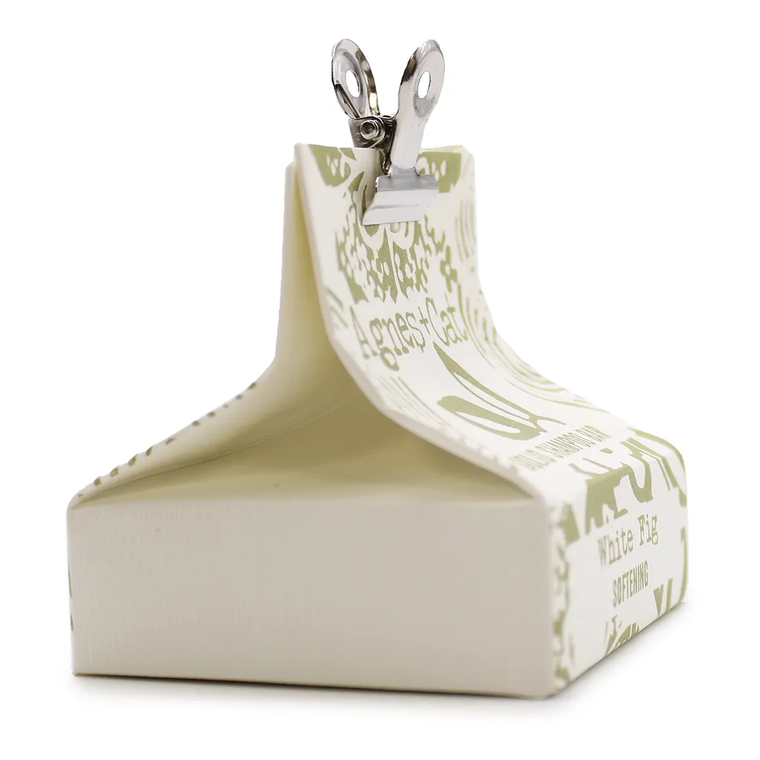 En solid shampoo-bar i en rund form præsenterer sig med en glat, hvid overflade. Den har en let skinnende tekstur, hvilket indikerer høj kvalitet. På overfladen findes en diskret, graveret tekst, der angiver navnet på produktet. Baren hviler på en naturlig, lys træoverflade, der skaber en kontrast til den hvide shampoo.