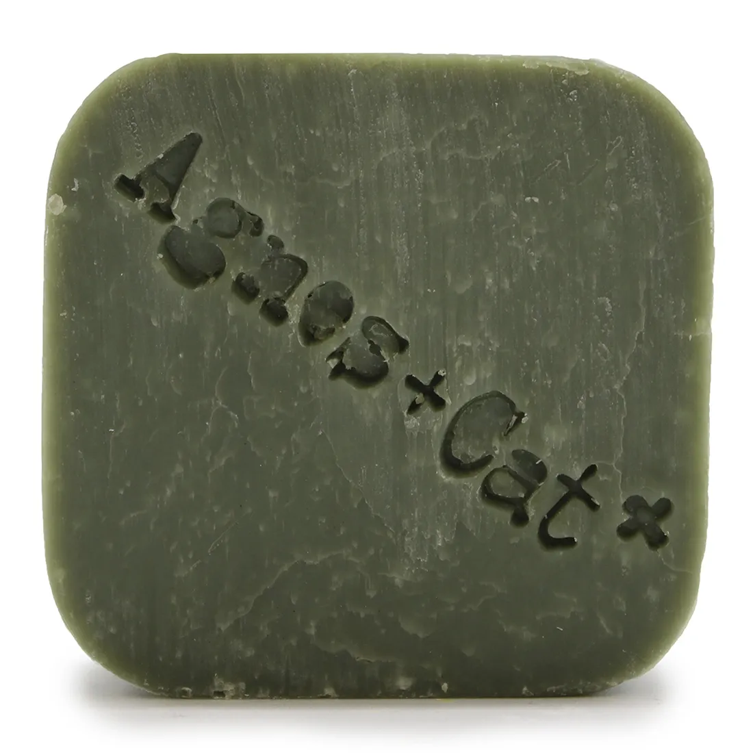 En solid shampoo bar i en hvid farve med en glat, rund form. Overfladen er let struktureret med små, fine prikker, der giver en interessant tekstur. Der er indgraveret et simpelt figurativt design, der ligner en kat. Shampoo baren er placeret på en lys, neutral baggrund, hvilket fremhæver dens rene og minimalistiske udseende.