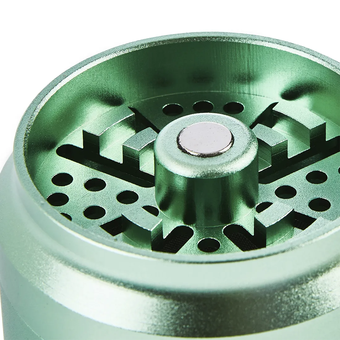 Grinderen har en rund form med en lys grøn overflade. Den er fremstillet af metal og har en glat tekstur. Øverste del er prydet med et mønster af små huller, der fungerer som malingskanaler. Kanten er let buet, og der er en skridsikker overflade forneden. Indeni ses tandformede knive, der er designet til at male.