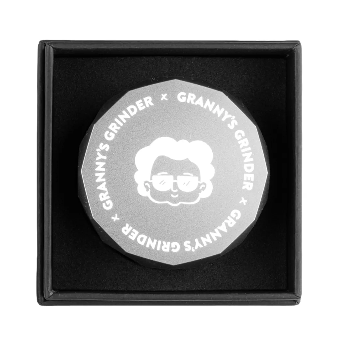 En sølvfarvet krydderkværn med en diameter på 55 mm. Overfladen er glat og skinnende med en let børstet finish. Kværnen har en hexagon-formet mønster på toppen, der giver et moderne udtryk. Der er to sektioner, der åbnes med en skrue, og indvendigt ses skarpe tænder til kværning af urter.