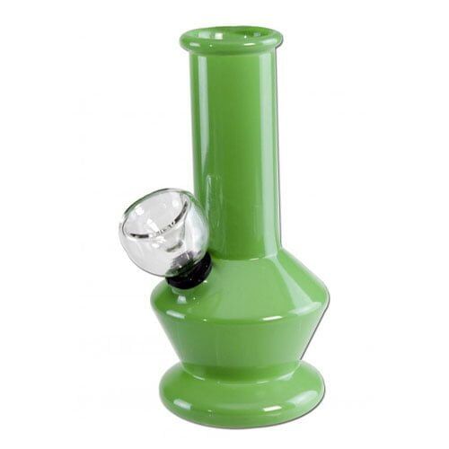 En lille bong i klart glas præsenterer sig med en slank, cylindrisk form og en vægt på detaljer. Den har en dyb grøn nuance i bunden og en glat overflade, der reflekterer lys. En afrundet skål er placeret på siden, mens en lige hals strækker sig opad. Formen giver en elegant og minimalistisk æstetik.