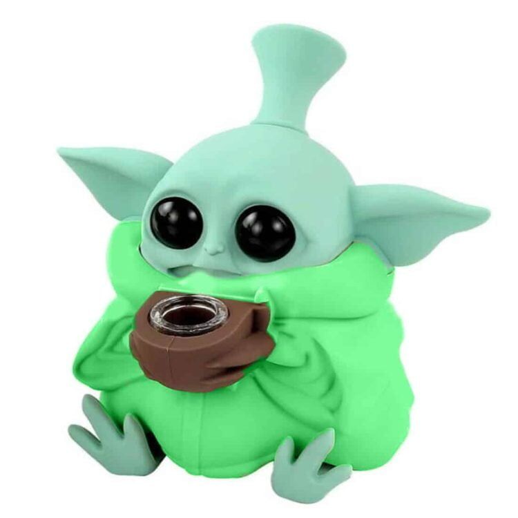 En grøn silikonebong i en slank, buet form, cirka 13 cm høj. Overfladen har en blød tekstur, der fremhæver den fleksible silikone. Bongen har en rund bund for stabilitet og en smal, lige hals. Indsatsen til vand og en mundstykkeåbning er tydelige. Farven er ensartet, med en mat finish, der skaber et moderne udtryk.