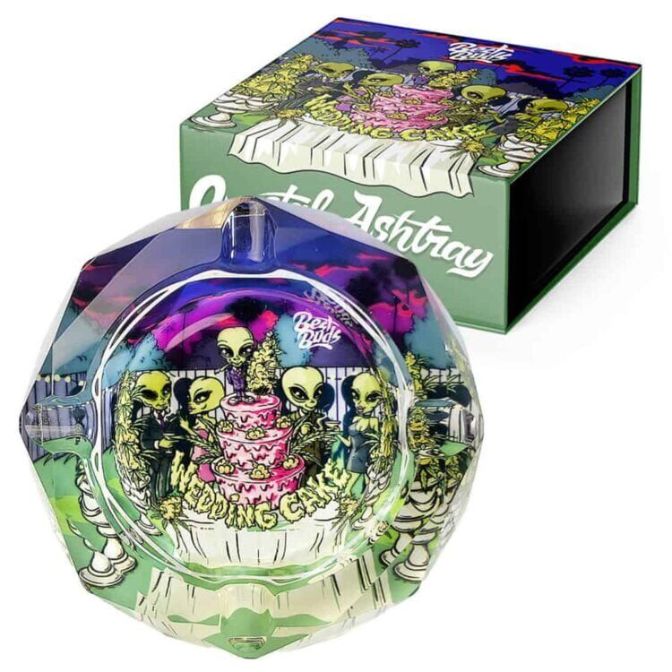 Krystalaskebægeret præsenterer en klar, glat overflade med facetter, der reflekterer lys og skaber et glitrende udtryk. Formen er rund med en flad bund, og væggene er let skrå. Kanterne er polerede og har en elegant finish. Askebægeret har en indgravering, der skaber et diskret mønster og tilføjer en dekorativ detalje.