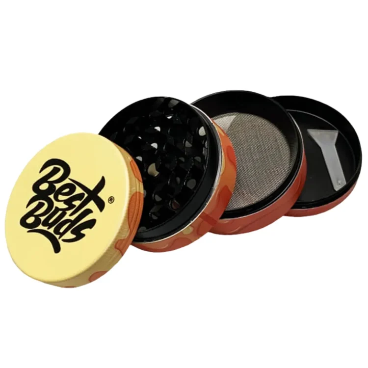 En kompakt, rund krydderkværn med en diameter på 50 mm. Overfladen er dækket af en glat, skinnende, gennemsigtig gelato-farve med nuancer af mango og fersken. Kværnen har en fine, skarpe tænder, der er synlige indeni. Den øverste del har et let buet låg med en lille knap til åbning, og der er ingen synlige mærker eller logoer.