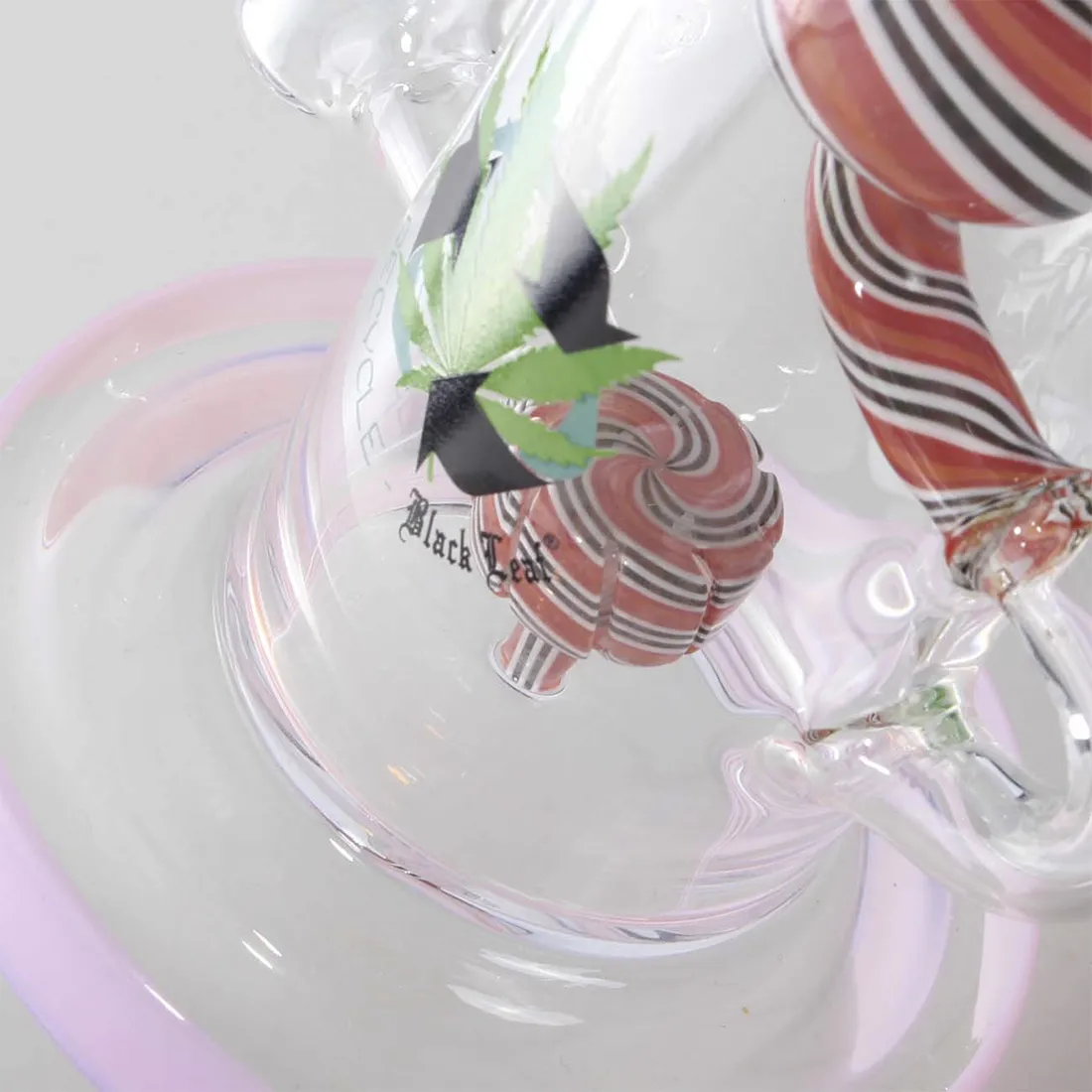 En høj, slank bong i sort glas prydet med et bladmotiv i lyserød. Den har en rund base, der gradvist snævrer ind mod en smal hals. Overfladen har en blank finish, som reflekterer lys. Der er en indbygget skål til rygning, og bongen har en tydelig, krum form, der skaber et elegant udseende.