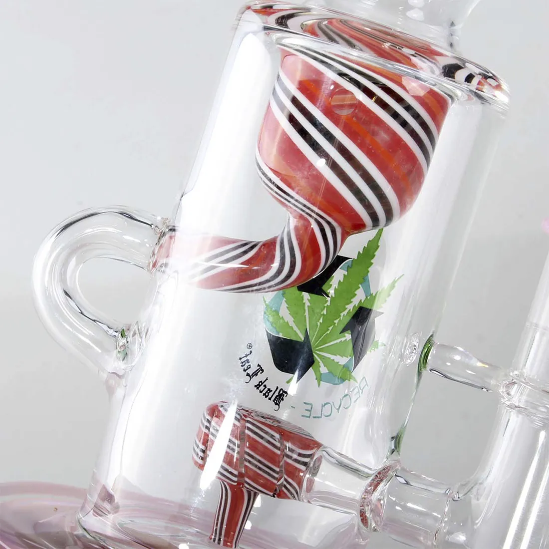 En sort bong med bladrankemønster prydet i pink nuancer. Den har en glat, skinnende overflade med en cylindrisk form, der afsluttes i en bred åbning øverst. Bunden er stabil og bred, hvilket giver støtte. Der er en skarp kontrast mellem den matte sorte farve og de levende pink detaljer, der tilføjer visuel interesse.