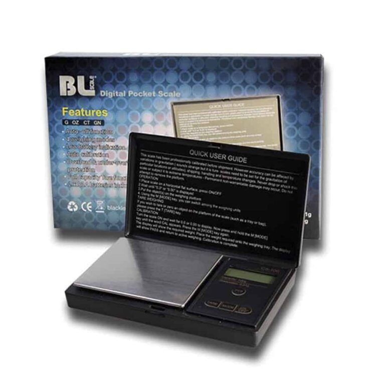 En digital præcisionsvægt præsenterer en flad, rektangulær platform med en sølvgrå overflade og afrundede kanter. Den har en klar LCD-skærm, der viser vægtmålinger i sorte tal på en hvid baggrund. Vægten har en afbryderknap og en nulstillingsknap, placeret på en af de korte sider. Under platformen ses fire skridsikre gummifødder for stabilitet.