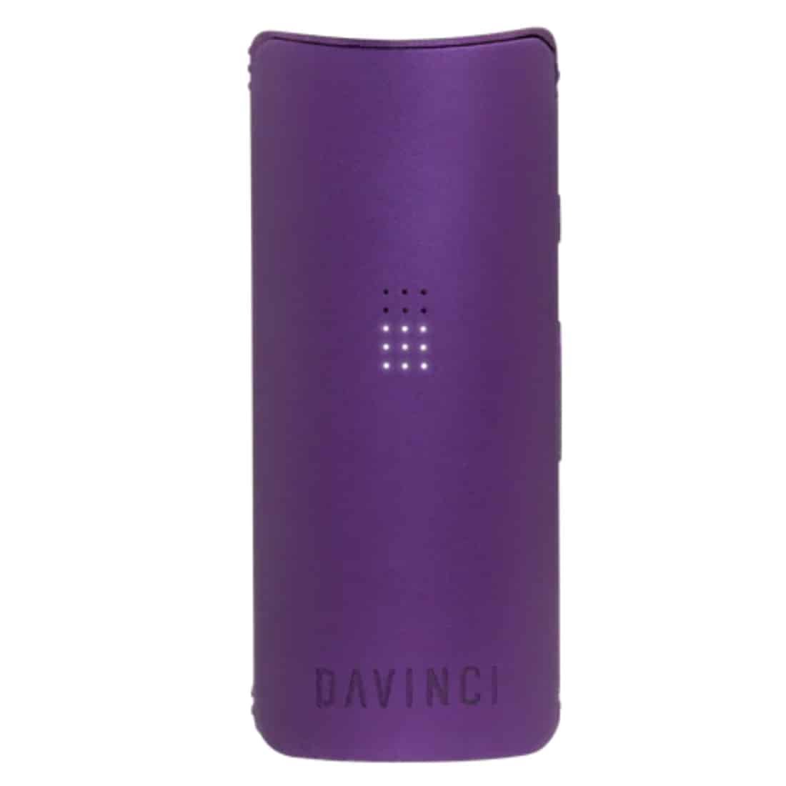 En lille, kompakt enhed med en glat, amethystfarvet overflade dominerer scenen. De runde kanter giver et strømlinet udseende, mens en metalramme tilføjer kontrast. Flere små knapper og en skærm er placeret på enheden, hvilket giver mulighed for interaktion. Den matte tekstur står i kontrast til det glinsende metal, hvilket skaber en visuel dybde.